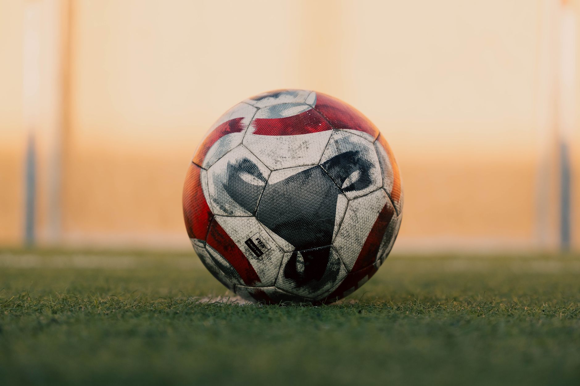 Close-up of a soccer ball on a grassy field in Libya during sunset.